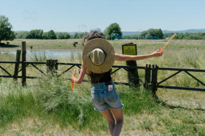woman running through field making bubbles